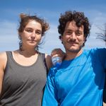 Three friends posing together outdoors on a sunny day in Portugal, embracing and smiling.